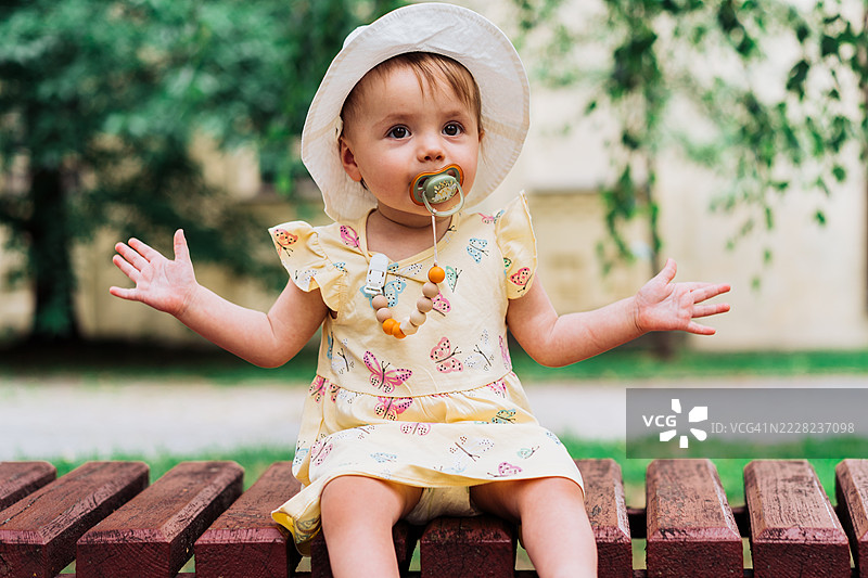 可爱的婴儿戴着帽子，在公园环境中享受户外时光图片素材