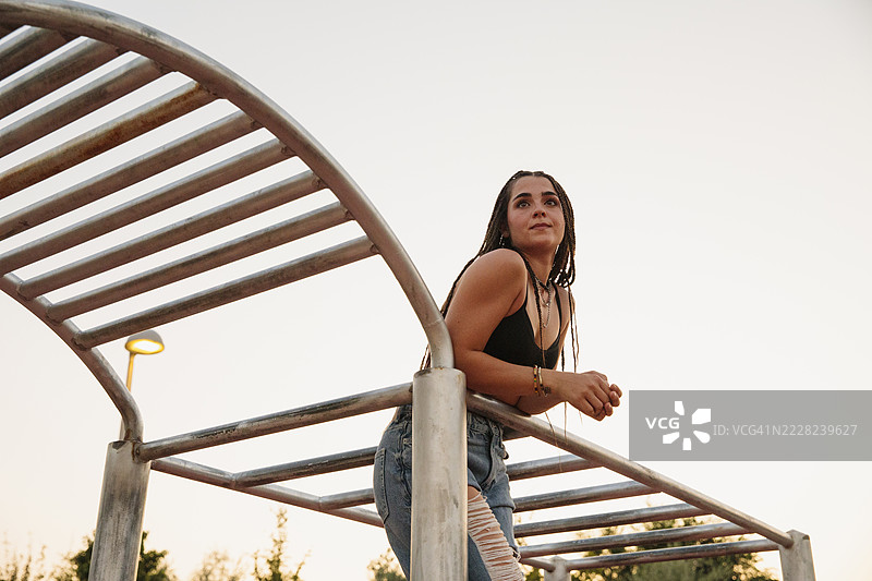 年轻的运动女性在城市健身设施上日落时休息图片素材