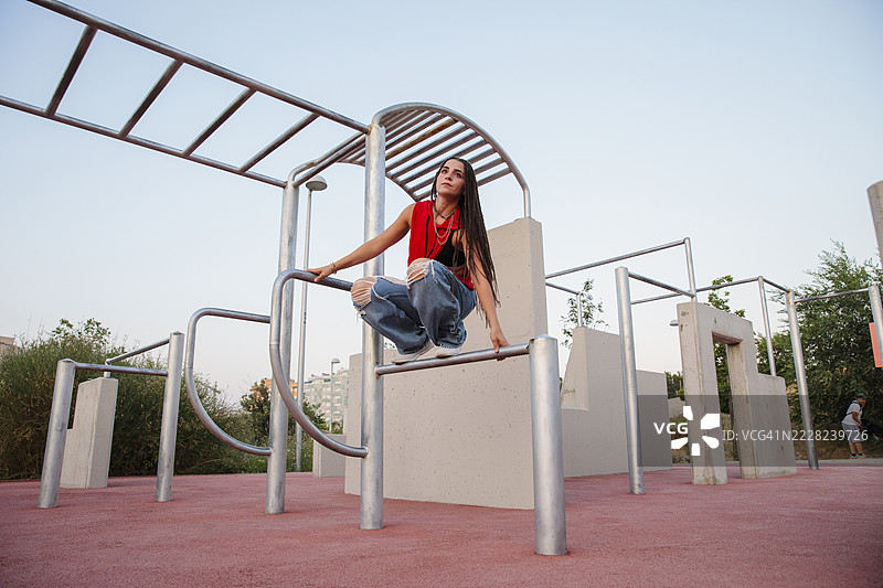 年轻女性在日落时分的城市健身器材上保持平衡图片素材