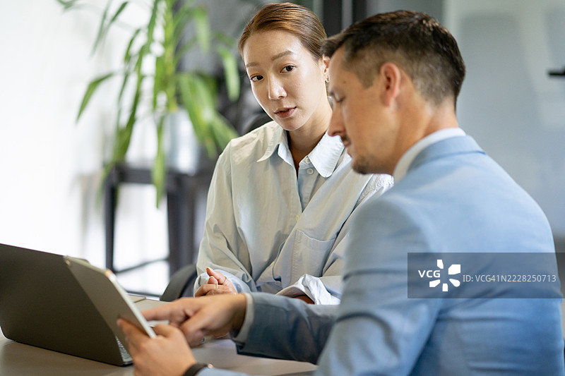 商务同事在现代办公室中使用平板电脑进行协作图片素材