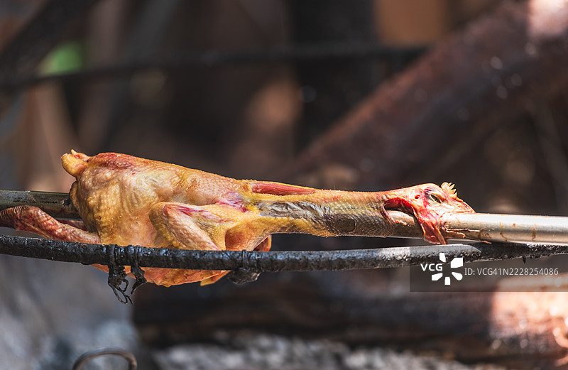 金属串上的烤鸡腿在明火上烤制图片素材