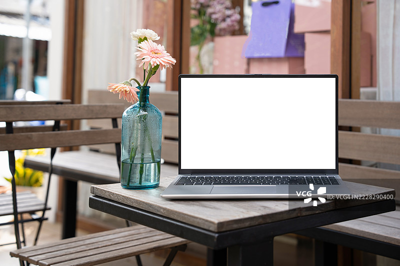 咖啡馆背景下桌子上的笔记本电脑空白屏幕。咖啡店桌子上的笔记本电脑空白屏幕，背景模糊。图片素材