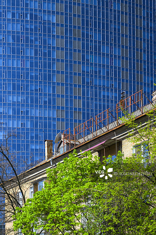 老旧住宅楼与其背后高耸的现代办公楼图片素材