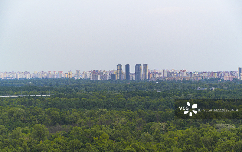 城市景观主导着广阔的森林，天空晴朗。图片素材