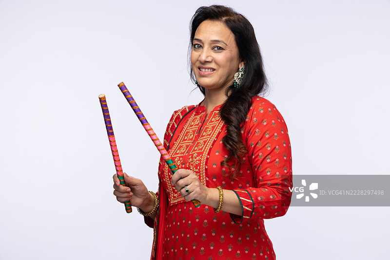 美丽的印度女性穿着传统的裙子和上衣在白色背景下表演丹迪亚舞的库存照片图片素材