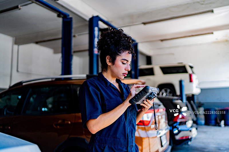 年轻女机械师在汽车修理店使用扫描仪图片素材
