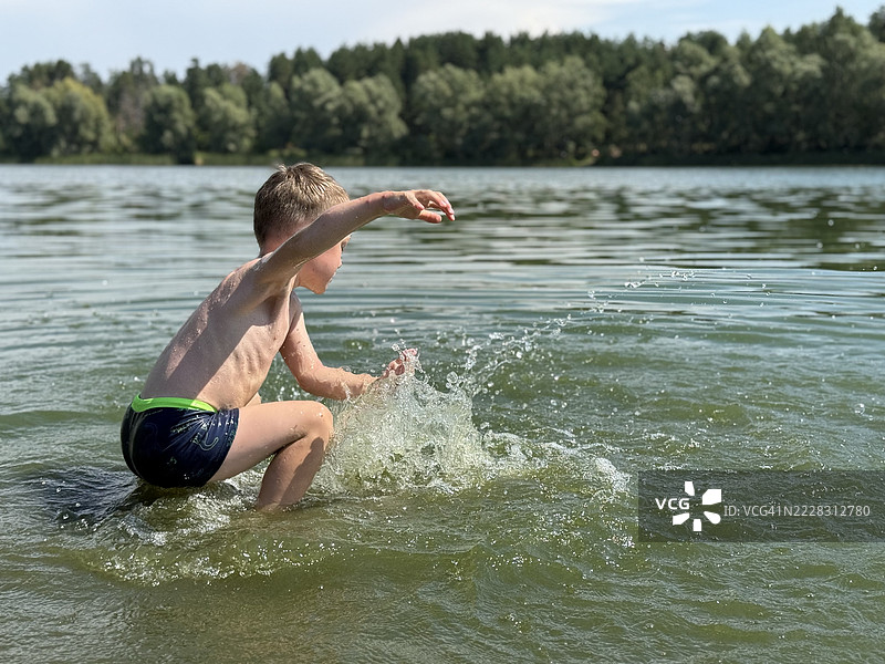 小男孩在湖边玩水图片素材