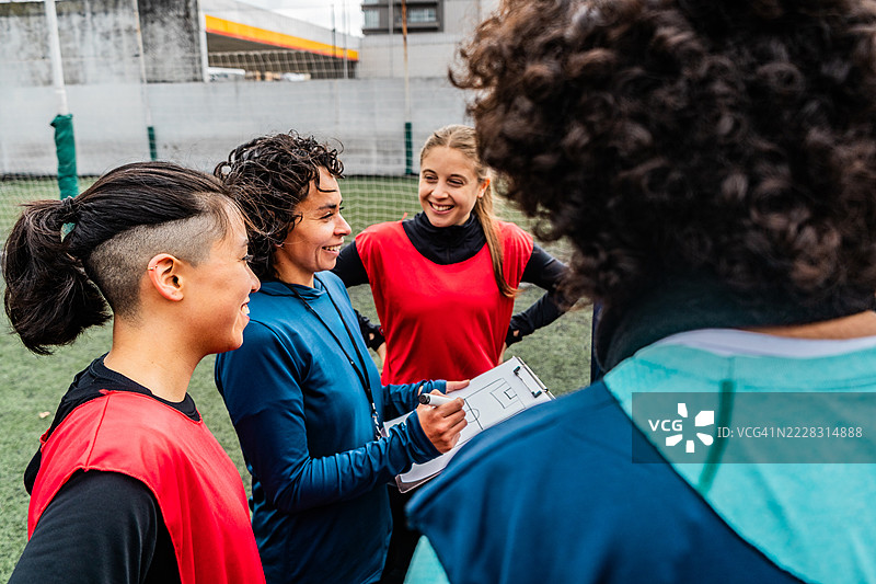 女教练在夹板上为混合足球队绘制战术图。图片素材