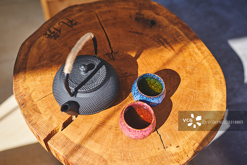 传统茶壶和陶瓷杯在自然光下的粗糙木桌上图片素材