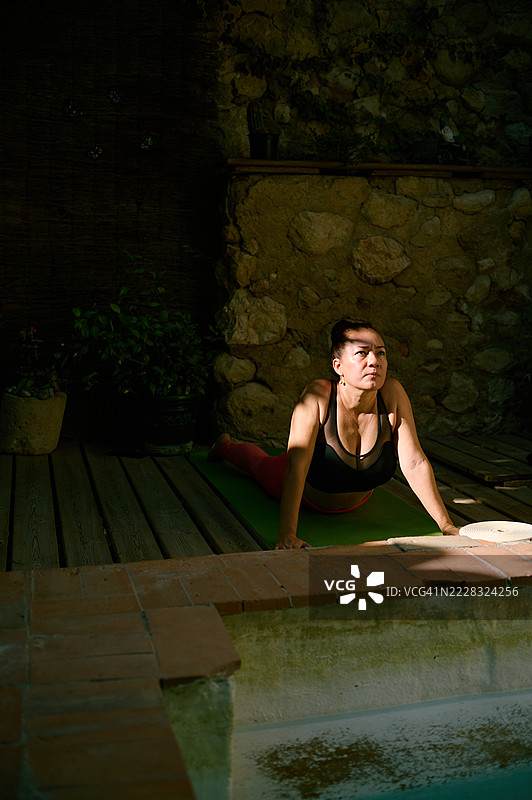 在自然光和石墙的户外空间中练习瑜伽的女性图片素材