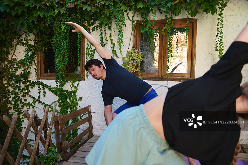 户外瑜伽课程，团体在郁郁葱葱的花园中拉伸图片素材