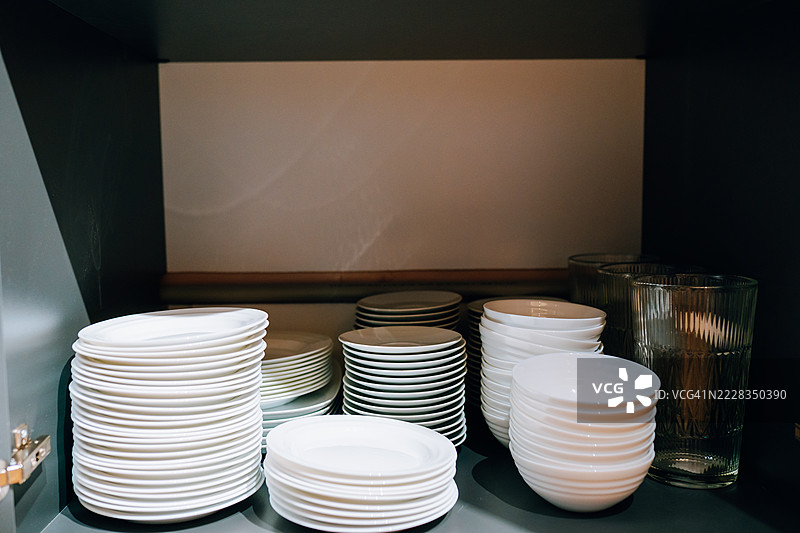 厨房橱柜内堆放着白色的盘子、碗和杯子图片素材