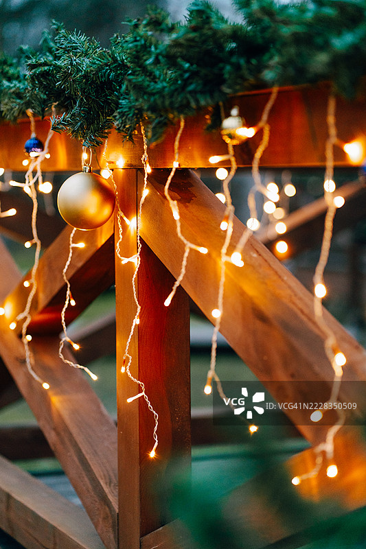 节日期间，圣诞灯和金色球装饰着木栅栏图片素材