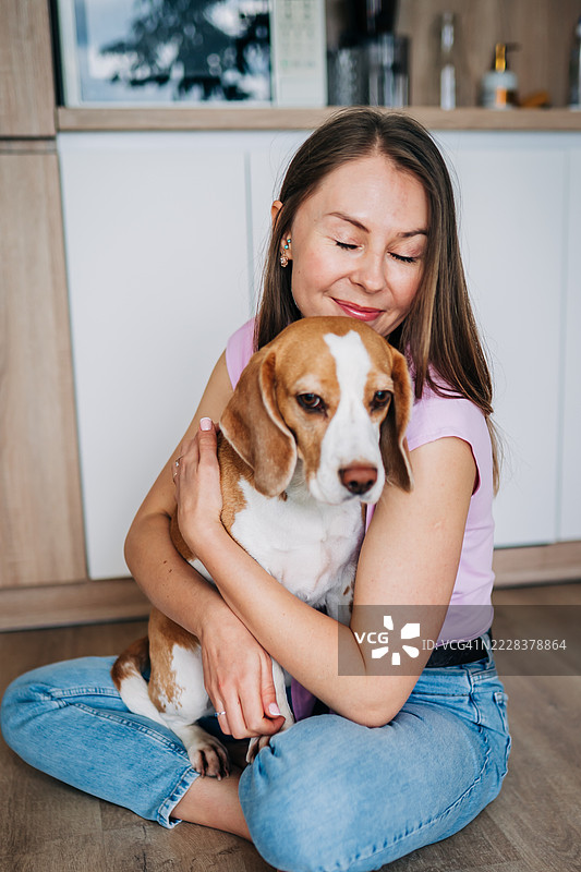 女人在温暖而充满爱的场景中拥抱一只比格犬图片素材