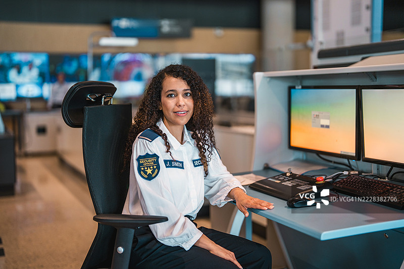 年轻的西班牙裔女性机场安检员穿着制服在现代控制室内工作图片素材