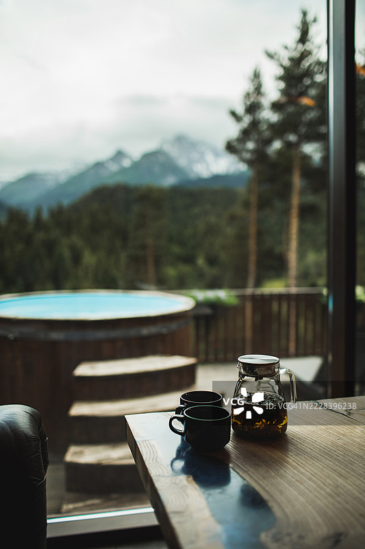 桑拿小屋内的热草药茶，外面是带有壮丽山景的热水浴缸图片素材