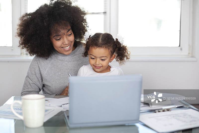 年轻母亲在工作同时陪伴女儿图片素材