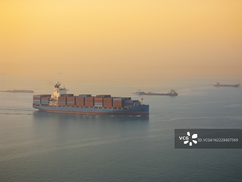 航拍视角的集装箱货船，满载集装箱，从商业港口的码头出发，适用于商业物流、进出口、运输或货运。图片素材