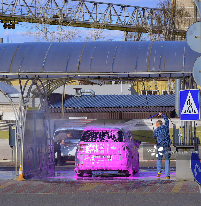 基辅，乌克兰的洗车员工正在用粉色洗涤泡沫覆盖汽车图片素材