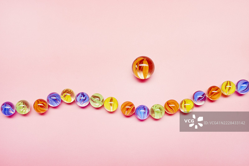 粉色背景上的波浪图案玻璃球，小球与大球的对比图片素材