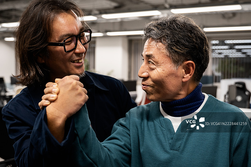 一张日本员工在办公室里手牵手的照片。图片素材