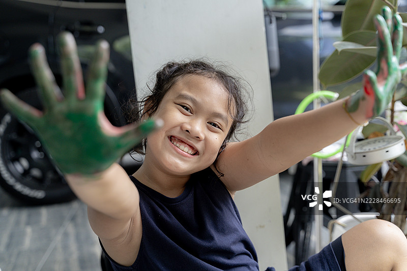 快乐的8岁女孩在家里给自己的手上色图片素材