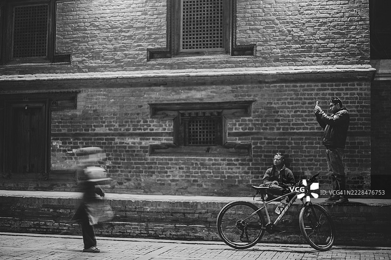 人们走过尼泊尔加德满都帕坦杜巴广场的新ar建筑。图片素材