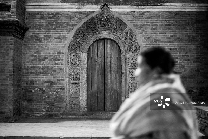 一个人走过尼泊尔加德满都帕坦杜巴广场的新ar寺庙建筑。图片素材