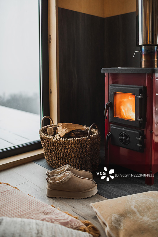 温暖的冬季毛靴靠近壁炉和装有木柴的藤编篮子图片素材
