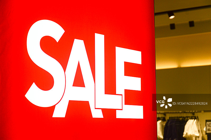 时尚商店促销：时令折扣，时尚服装。热闹的服装店提供限时折扣，醒目的促销标志。图片素材