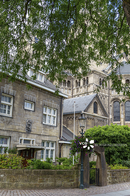 荷兰林堡省罗尔蒙德的风景如画的小巷中，教堂外观与树木和小巷灯。图片素材