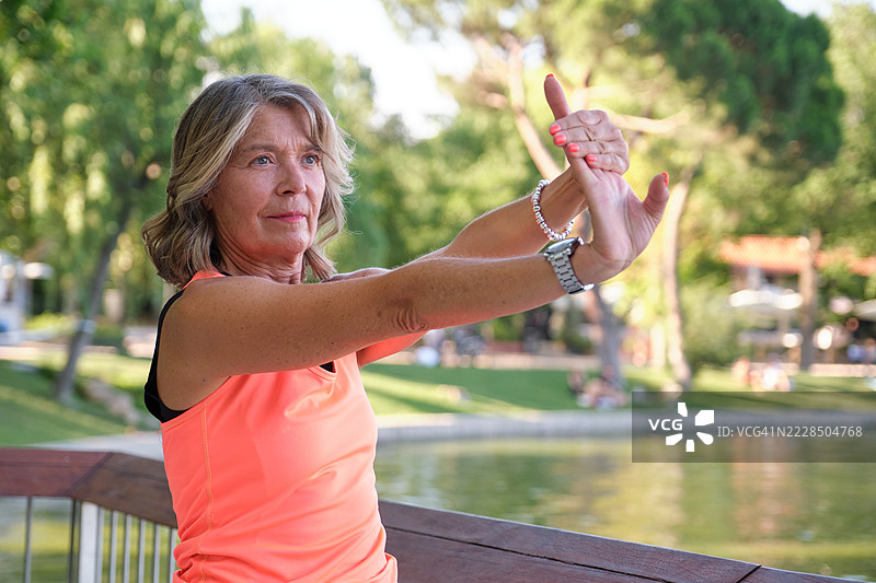 公园湖边的老年女性伸展手臂图片素材