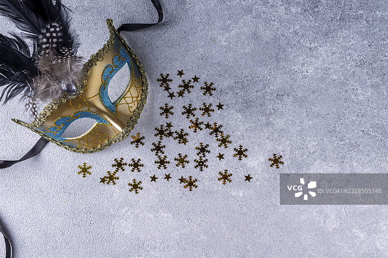 金色纸制圣诞面具，灰色背景上的五彩纸屑图片素材