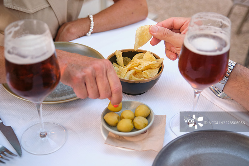 朋友们在餐桌上享受啤酒、薯片和橄榄图片素材