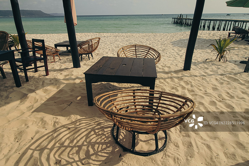 柬埔寨西哈努克市的考荣山洛姆，沙滩上有木椅和一张桌子，面朝碧蓝的海洋。图片素材