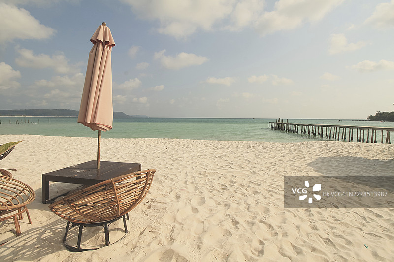 在柬埔寨西哈努克市的考荣山洛恩岛上，阳光明媚的夏日，孤独的伞和藤椅面朝广阔的海洋。图片素材
