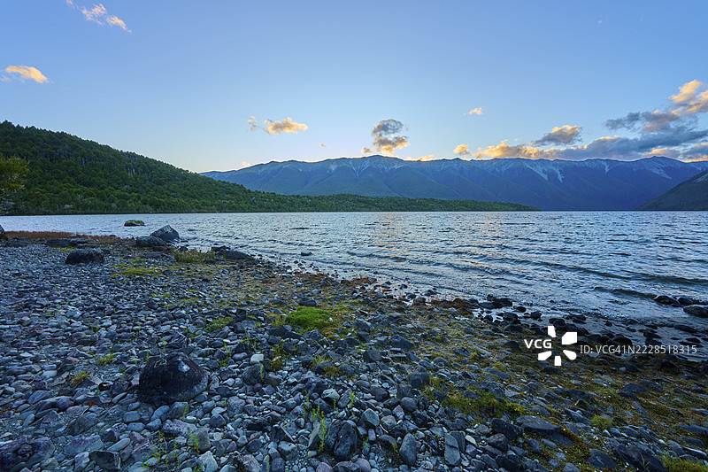 黄昏时分的岩石海滩，平静的湖泊与背景中的山脉，夏季，罗托伊提湖，圣阿尔诺，塔斯曼地区，新西兰南岛图片素材