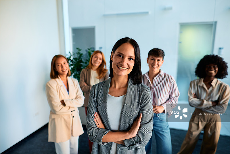自信的女商人在现代办公室微笑并交叉双臂图片素材