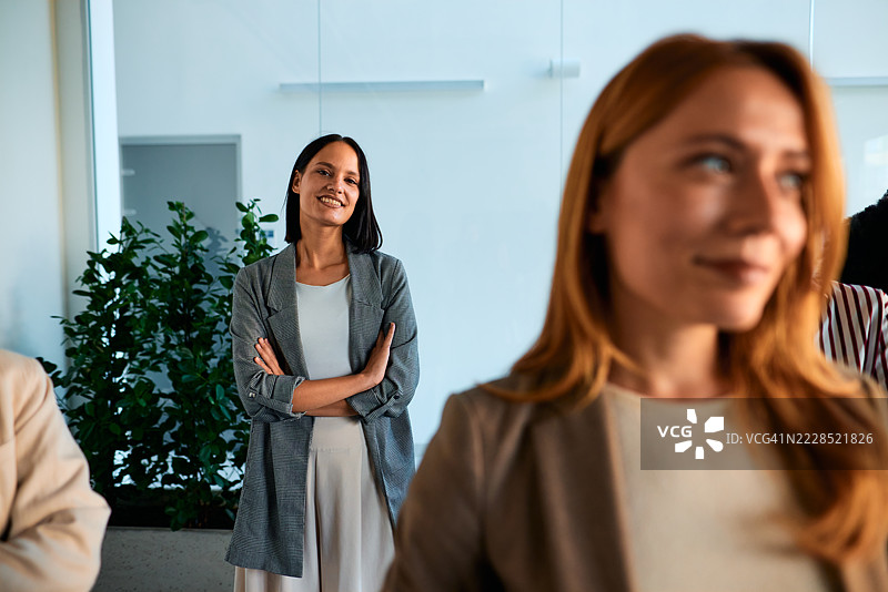 在办公室会议中微笑并交叉双臂的女商人图片素材