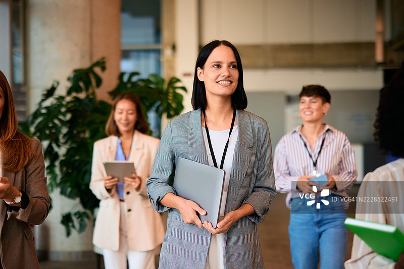 微笑的女商人在企业活动中手持笔记本电脑图片素材