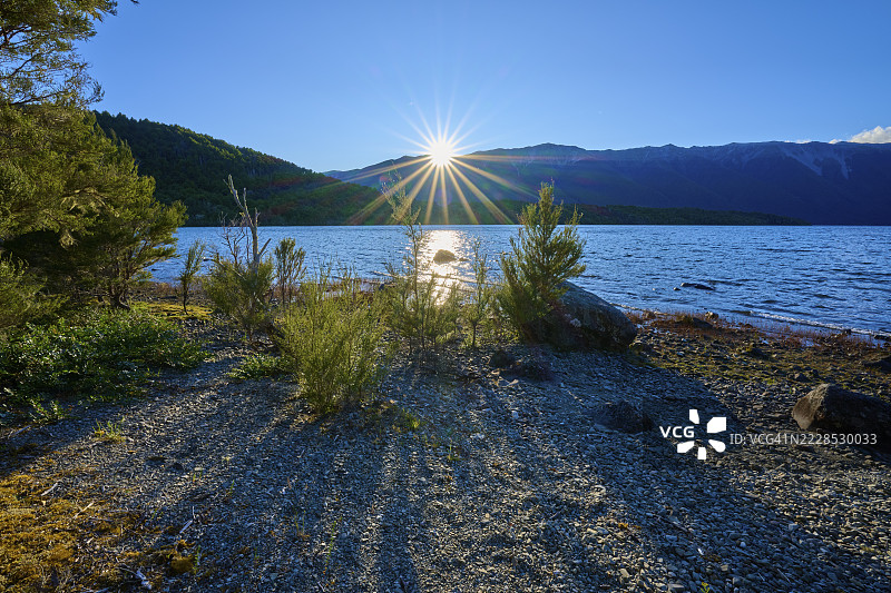 阳光洒在湖面上，前景有山脉和植物，夏季，新西兰南岛塔斯曼地区圣阿诺德的罗托伊蒂湖图片素材