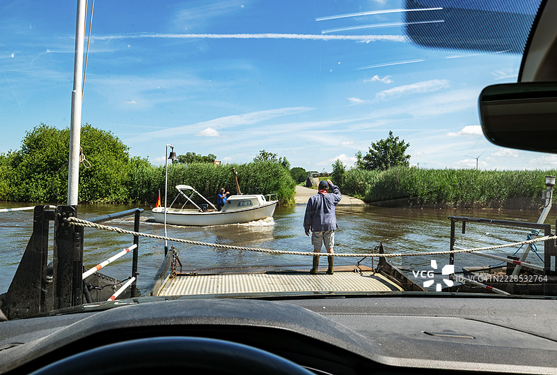绳索渡轮,普拉姆渡轮(Pram ferry Brobergen),横跨奥斯特河(Oste river),汽车在渡轮上的视角,渡轮工向驶过的摩托艇打招呼,施塔德区(district of Stade),下萨克森州(Lower Saxony),德国图片素材
