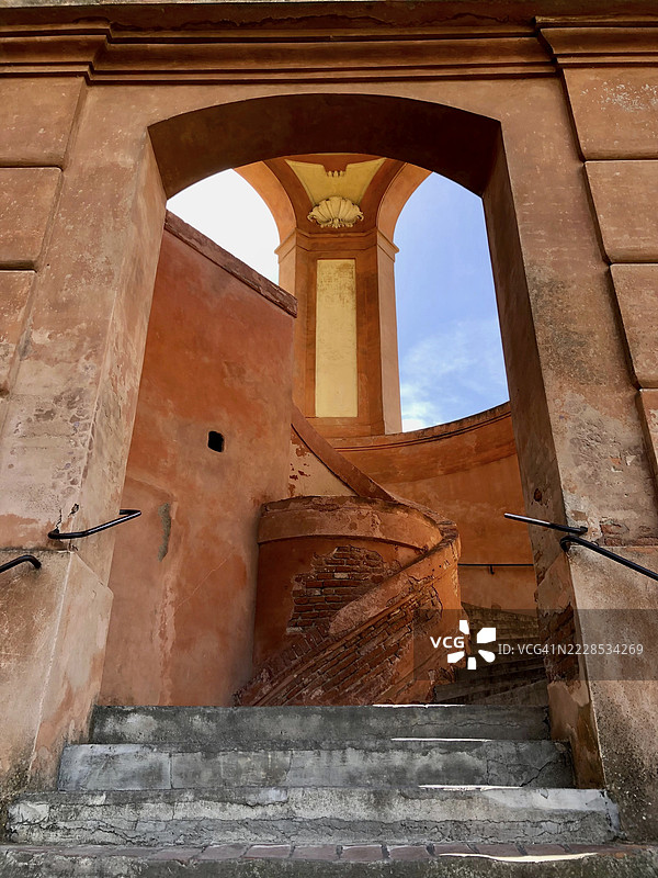 通过拱门看到内院的风化楼梯和红砖墙，圣卢卡圣母圣殿，科莱德拉瓜尔迪亚，博洛尼亚，意大利图片素材