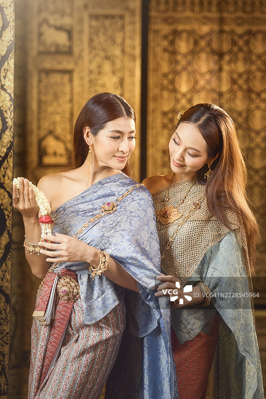 两位微笑的女性穿着传统泰国服饰，泰国图片素材