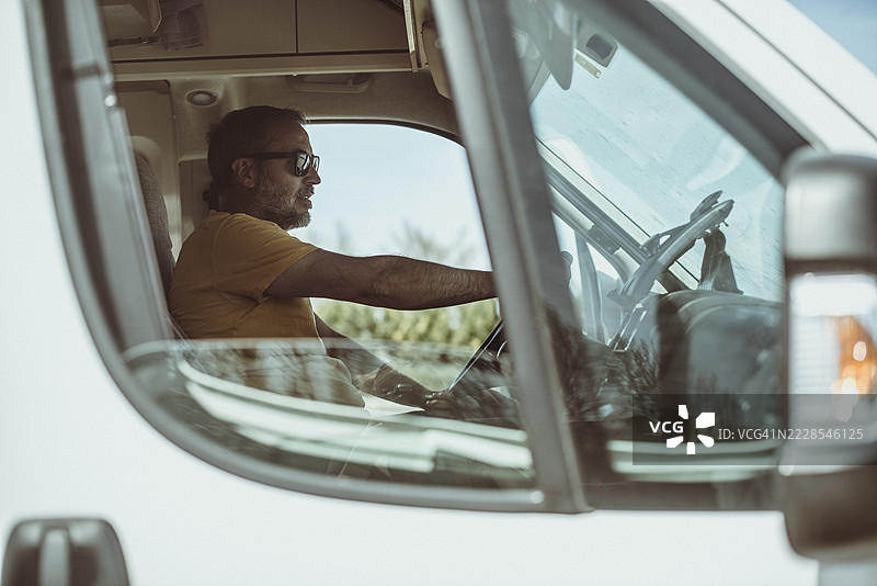从打开的窗户侧面看一位驾驶房车的男子图片素材