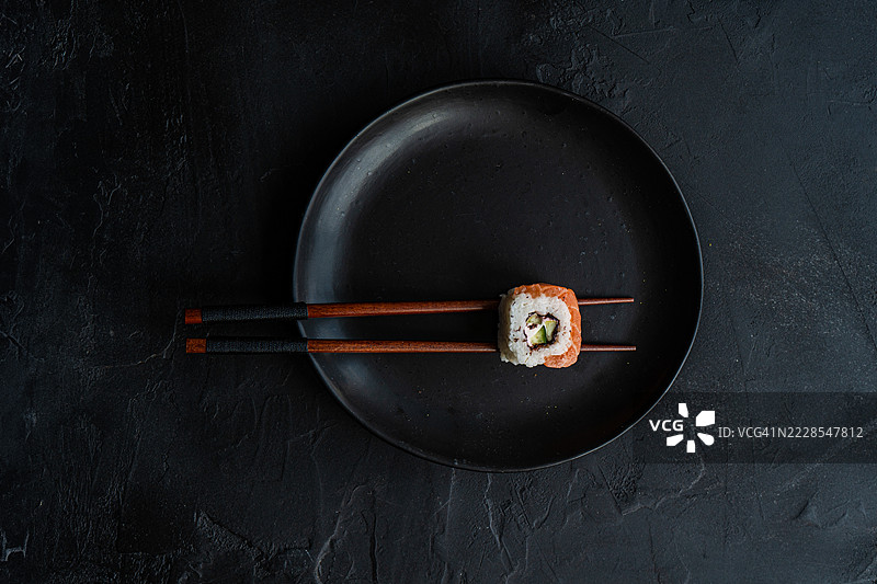 盘子上用筷子夹着一份加州三文鱼寿司的俯视图图片素材