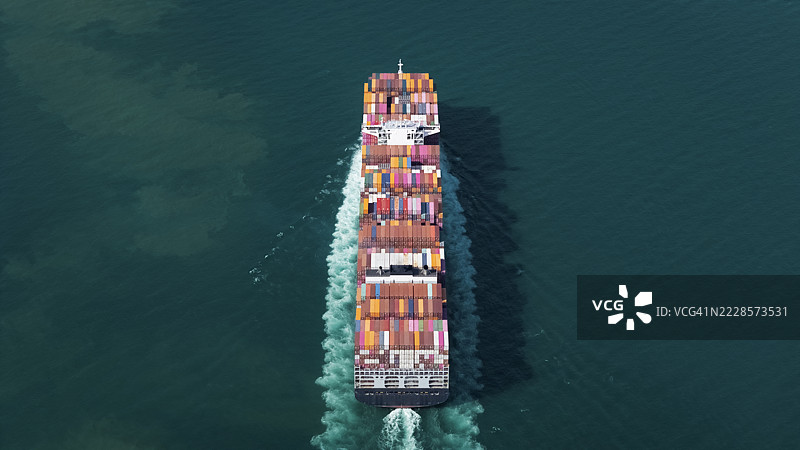 航拍视角的集装箱货船，满载集装箱，从商业港口的码头出发，适用于商业物流、进出口、运输或货运。图片素材