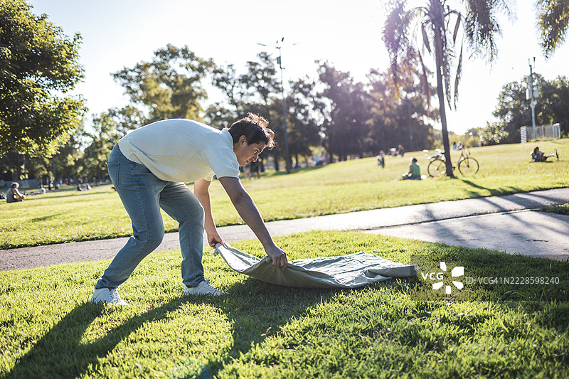 年轻的拉丁裔人们在公园的草地上铺上毯子图片素材