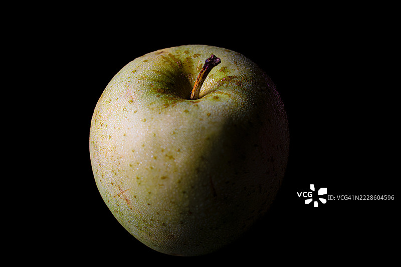 新鲜的绿色苹果上有水珠，背景为黑色图片素材