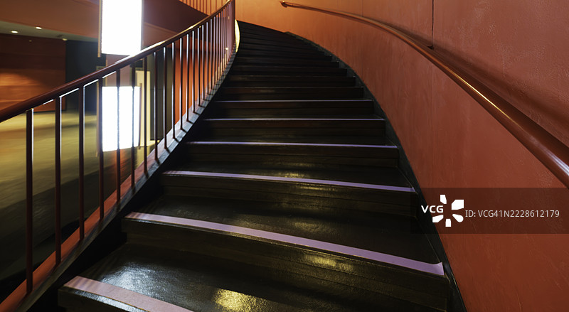 室内红墙旁的棕色螺旋楼梯图片素材